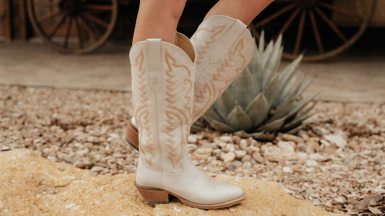 A woman standing on a rock wearing Evelyn 15" Western boot in ivory